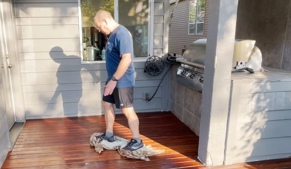 Wiping down a deck with a towel after staining