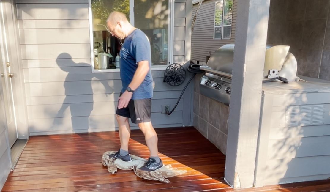 Wiping down a deck with a towel after staining